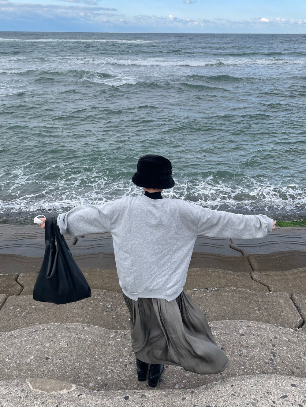 グレー系のスウェット、グレー系のスカート、ブラック系のハットを着用したレディースの秋コーディネートの2枚目の写真