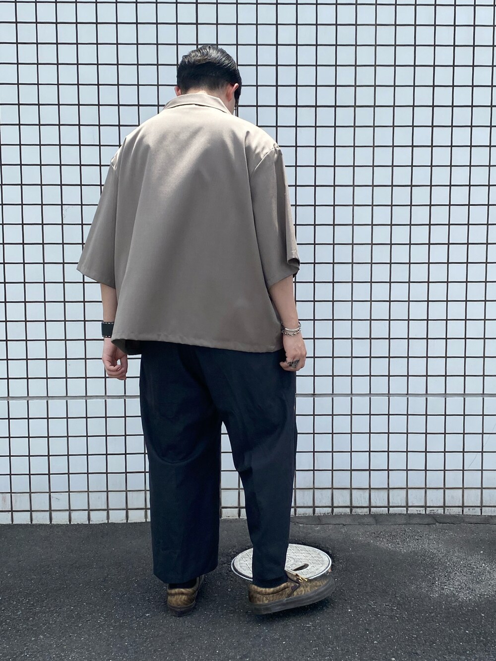 グレー系のスラックス、ゴールド系のスニーカー、グレー系のシャツ/ブラウスを着用したメンズの夏コーディネートの3枚目の写真