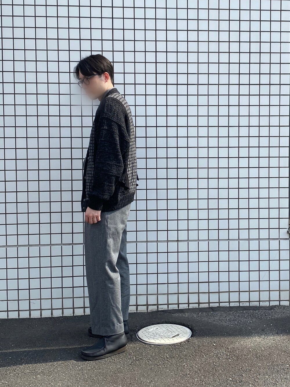 ブラック系のカーディガン/ボレロ、グレー系のスラックス、ブラック系のブーツを着用したメンズの春コーディネートの2枚目の写真