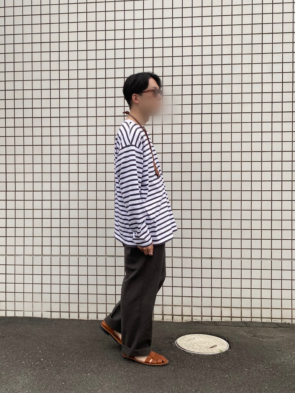 その他のTシャツ/カットソー、グレー系のスラックス、ブラウン系のサンダルを着用したメンズの春コーディネートの2枚目の写真