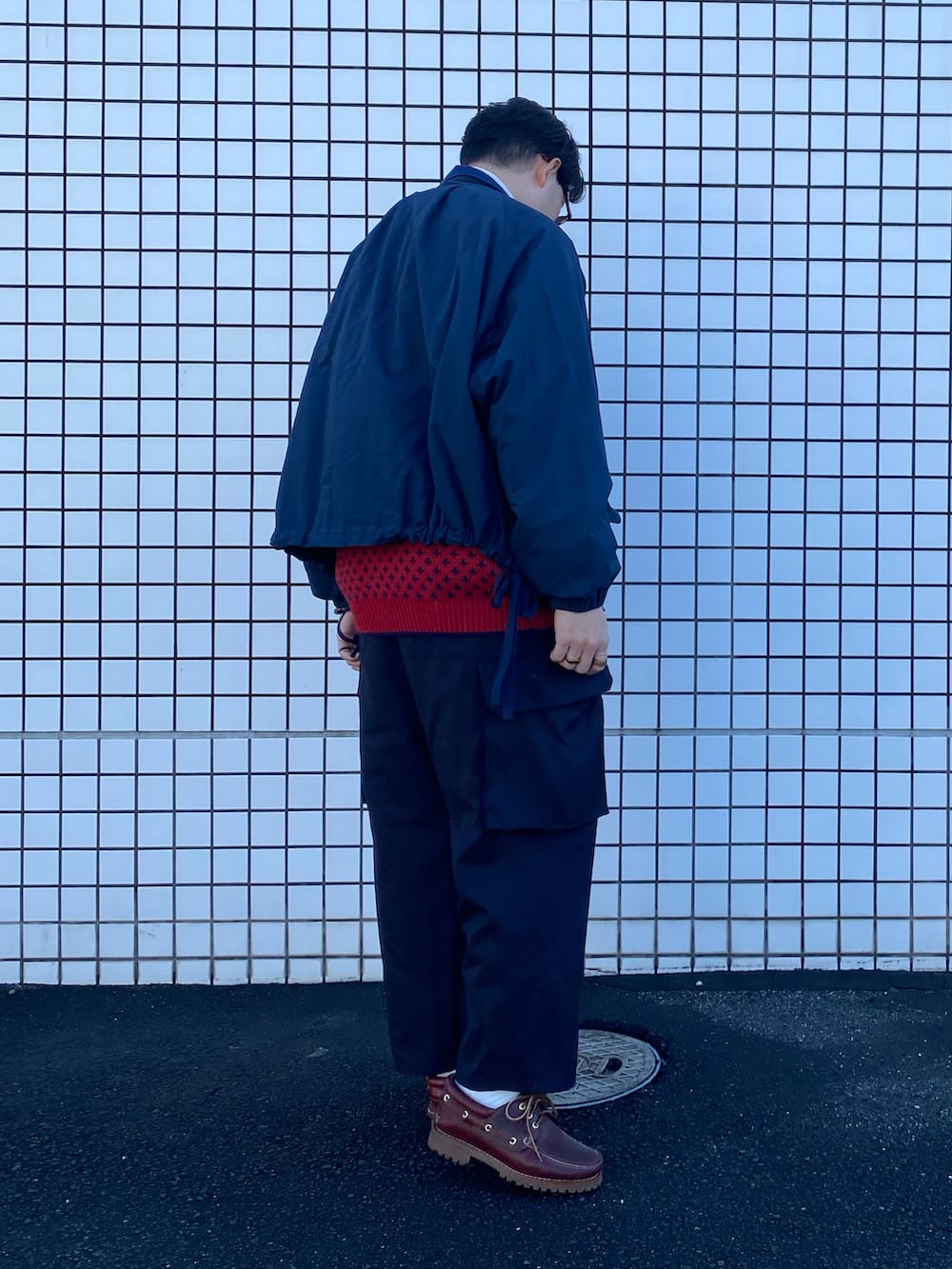 ブルー系のブルゾン、レッド系のニット/セーター、ブルー系のカーゴパンツを着用したメンズの冬コーディネートの2枚目の写真