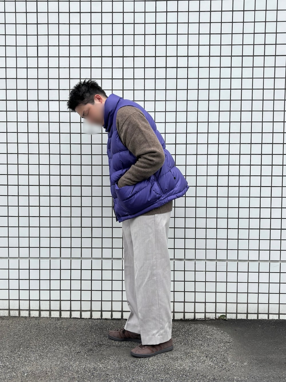 パープル系のダウンベスト、グレー系のスラックス、ブラウン系のスニーカーを着用したメンズの冬コーディネートの2枚目の写真