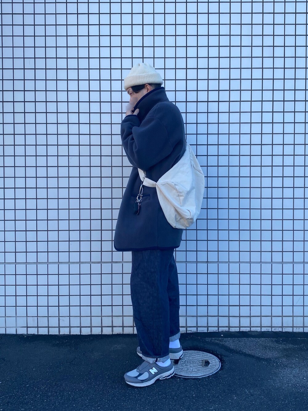 グレー系のダッフルコート、グレー系のニット/セーター、ブルー系のデニムパンツを着用したメンズの冬コーディネートの2枚目の写真