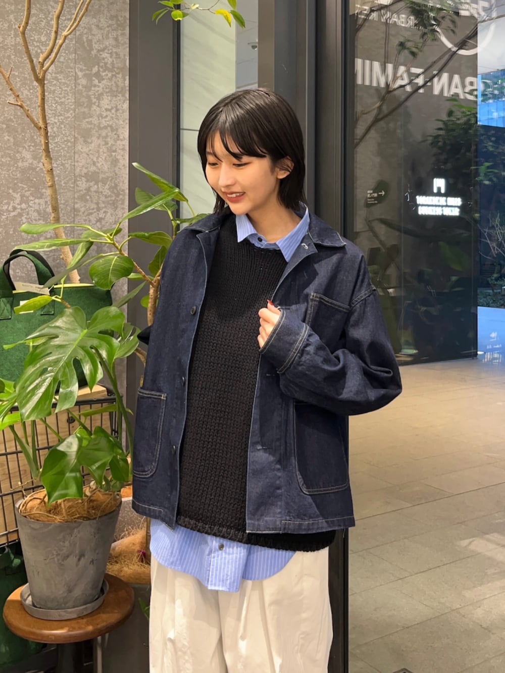 ブルー系のデニムジャケット、ブラック系のベスト、ホワイト系のその他パンツを着用したレディースの春コーディネートの2枚目の写真