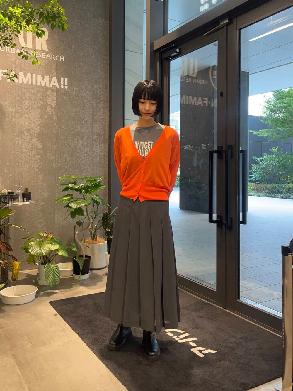 グレー系のスカート、グレー系のTシャツ/カットソー、ブラック系のブーツを着用したレディースの秋コーディネートの2枚目の写真
