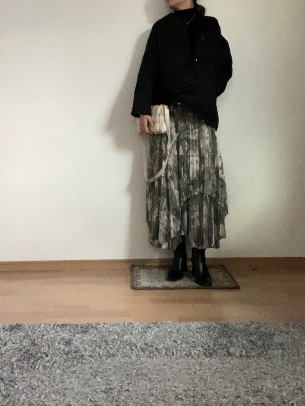 ブラック系のニット/セーター、グリーン系のスカート、ブラック系のブーツを着用したレディースの秋コーディネートの2枚目の写真