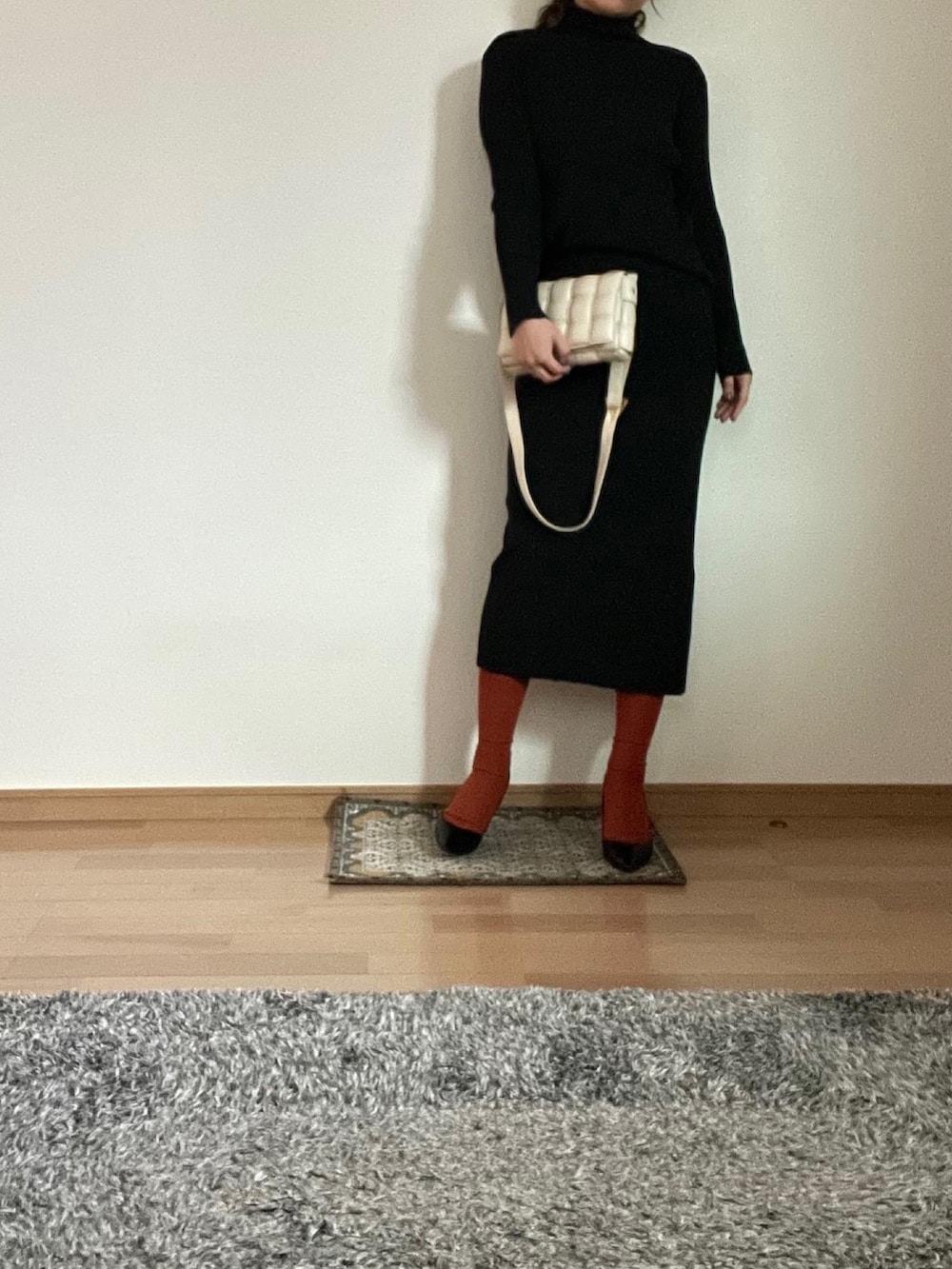 ブラック系のセットアップ、グレー系のチェスターコート、ブラック系のパンプスを着用したレディースの秋コーディネートの2枚目の写真