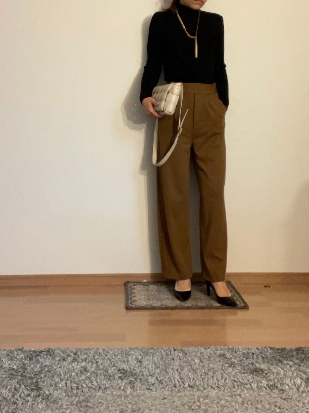 グレー系のチェスターコート、ブラック系のニット/セーター、ブラウン系のその他パンツを着用したレディースの秋コーディネートの2枚目の写真