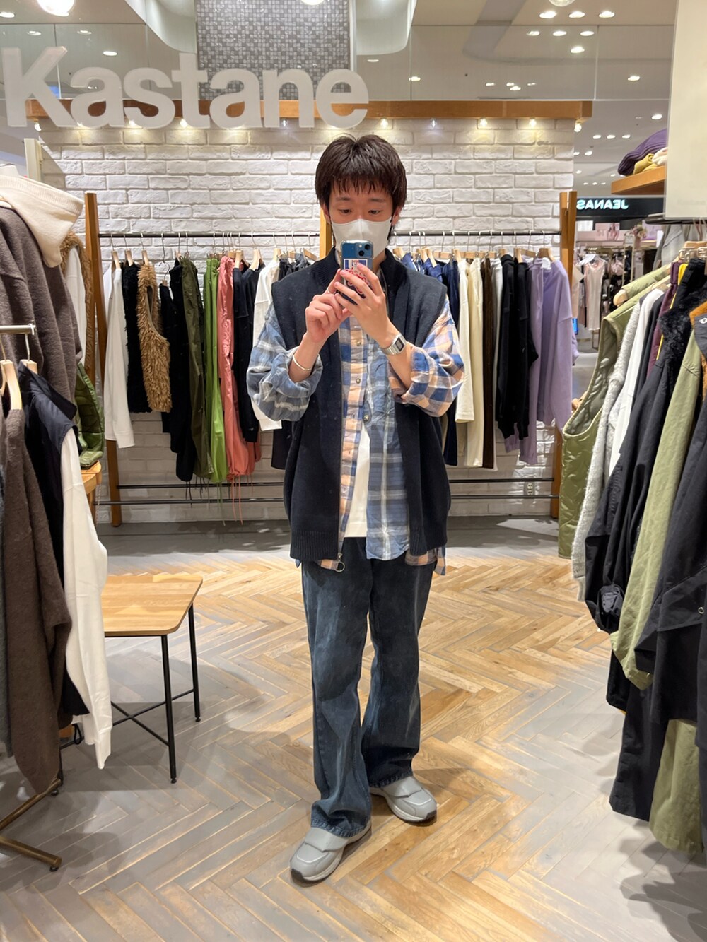 ブラック系のベスト、ブルー系のデニムパンツ、グレー系のスニーカーを着用したメンズの秋コーディネートの2枚目の写真