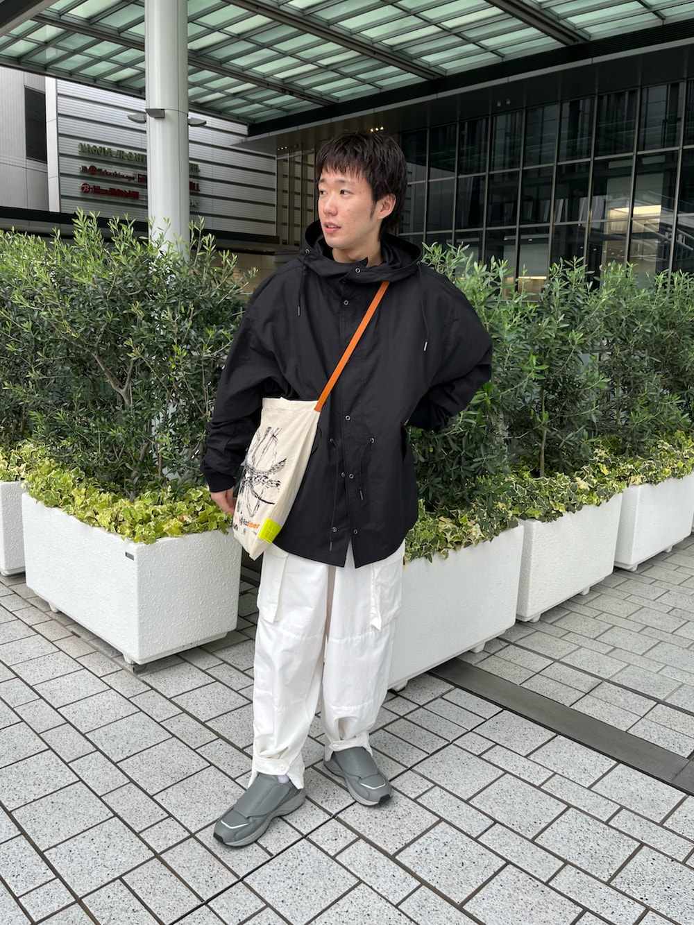 ブラック系のナイロンジャケット、ホワイト系のカーゴパンツ、グレー系のスニーカーを着用したメンズの秋コーディネートの2枚目の写真