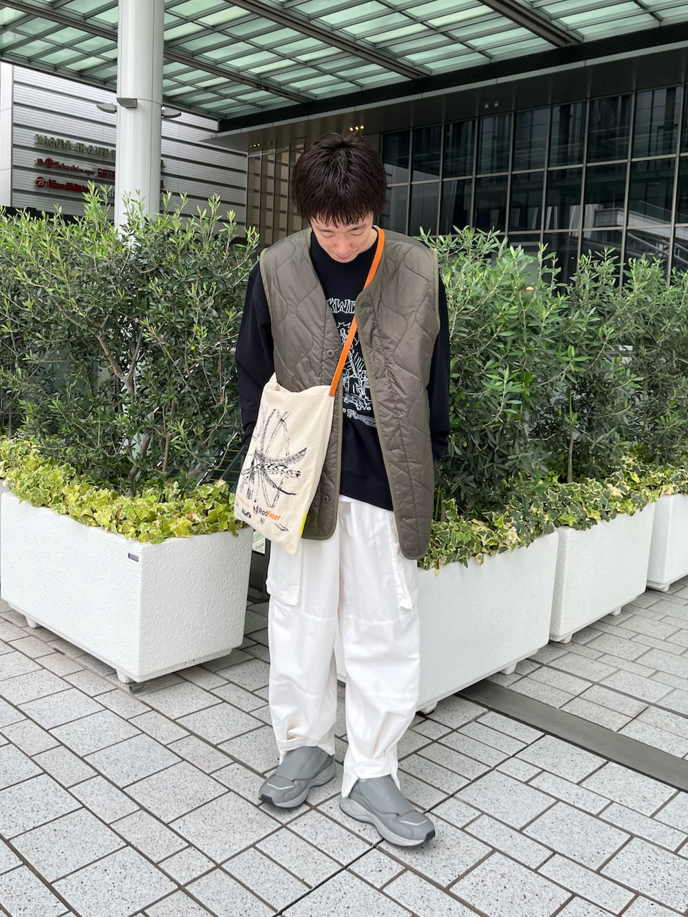 ブラック系のナイロンジャケット、ホワイト系のカーゴパンツ、グレー系のスニーカーを着用したメンズの秋コーディネートの3枚目の写真