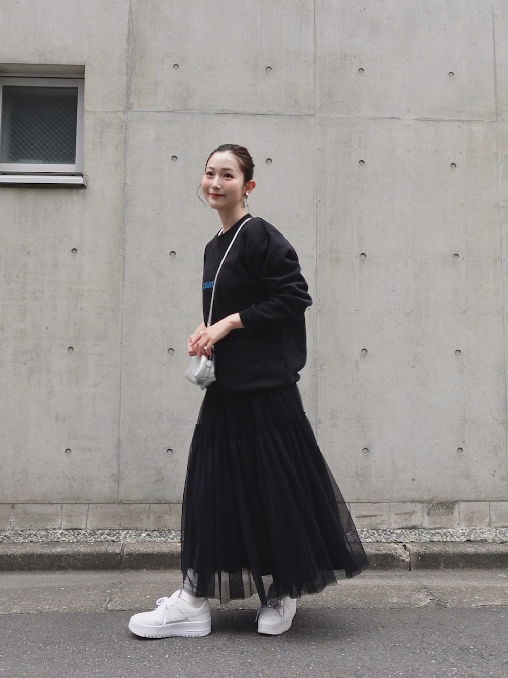 ブラック系のスウェット、シルバー系のショルダーバッグ、ブラック系のスカートを着用したレディースの春コーディネートの3枚目の写真