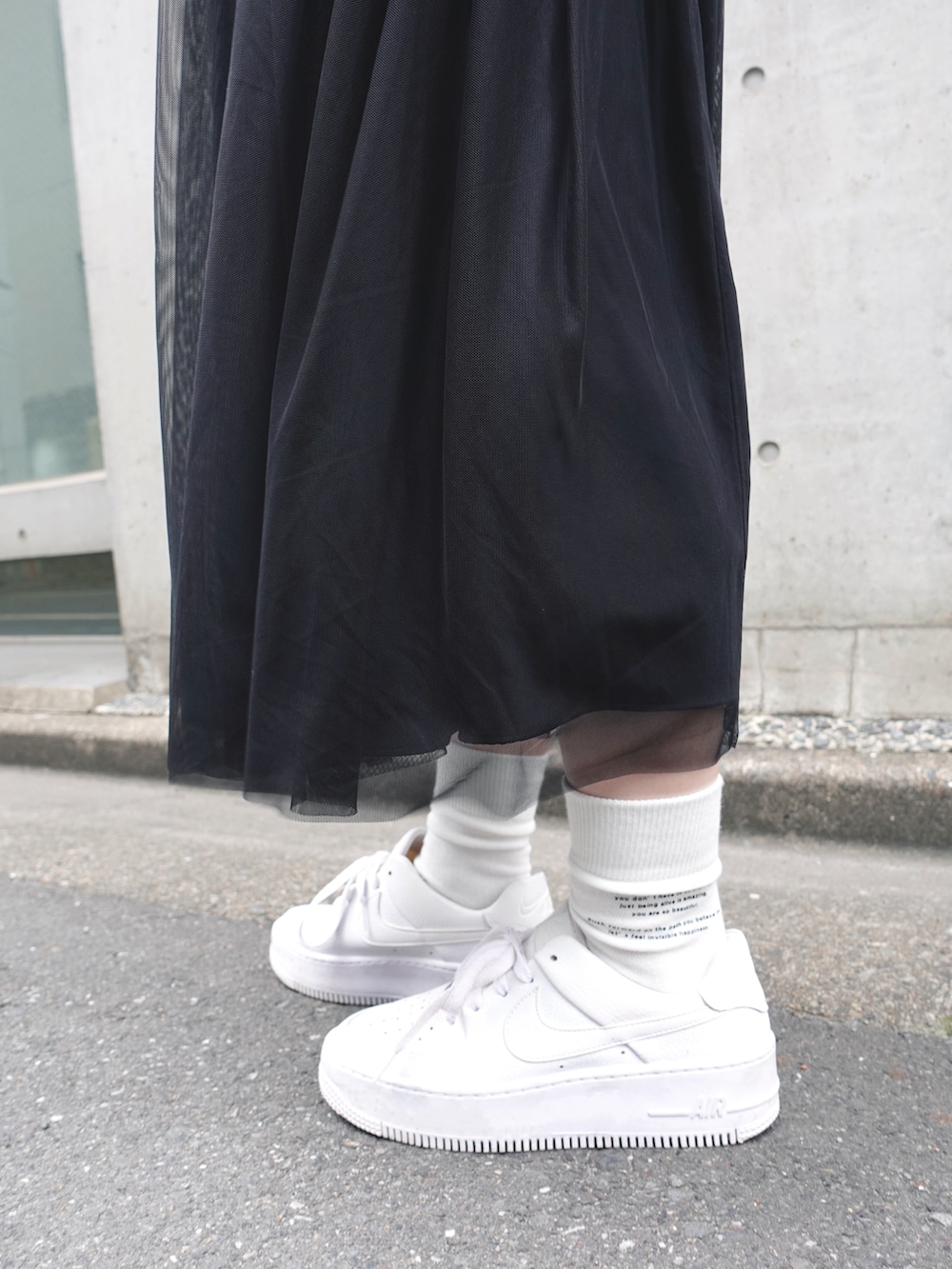 ブラック系のスウェット、シルバー系のショルダーバッグ、ブラック系のスカートを着用したレディースの春コーディネートの4枚目の写真