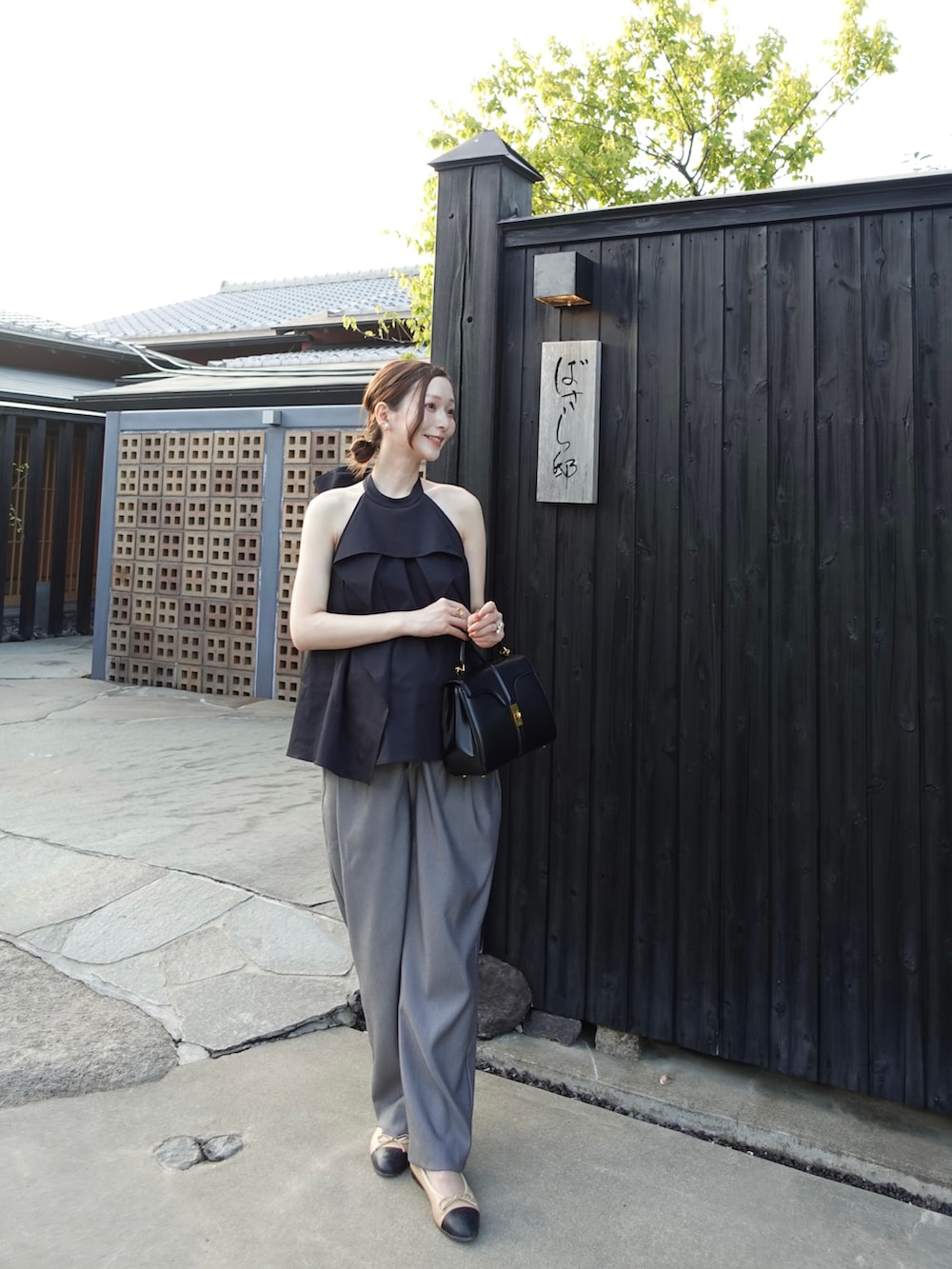 グレー系のスラックス、ブラック系のトップス、その他のシューズを着用したレディースの秋コーディネートの2枚目の写真