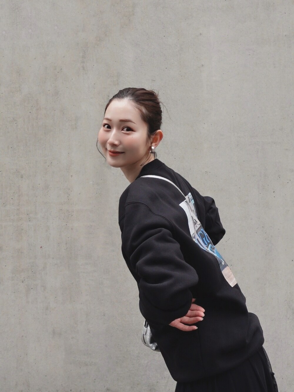 ブラック系のスウェット、シルバー系のショルダーバッグ、ブラック系のスカートを着用したレディースの春コーディネートの2枚目の写真