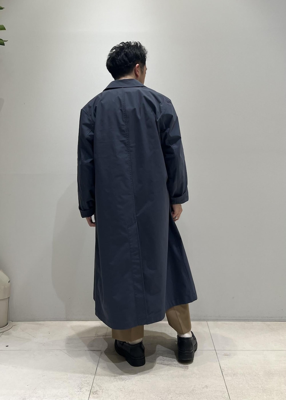 ブラック系のベスト、グレー系のステンカラーコート、イエロー系のスラックスを着用したメンズの春コーディネートの5枚目の写真