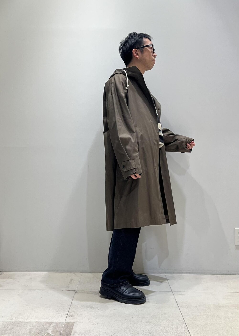 グリーン系のニット/セーター、ブラック系のローファー、ブルー系のデニムパンツを着用したメンズの冬コーディネートの7枚目の写真