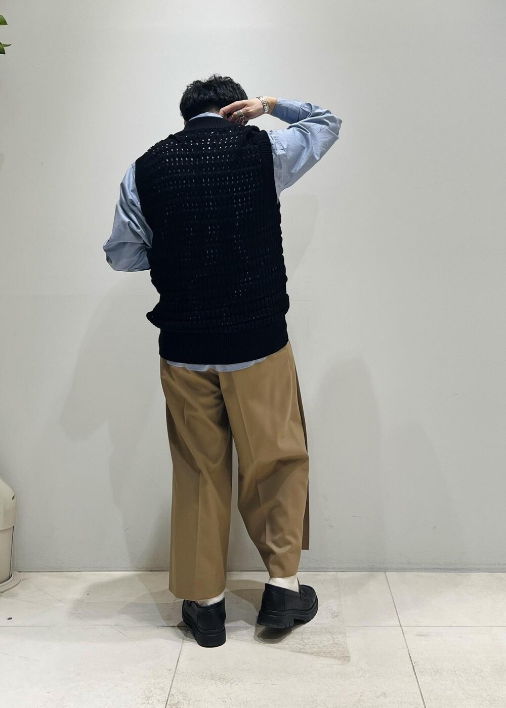 ブラック系のベスト、グレー系のステンカラーコート、イエロー系のスラックスを着用したメンズの春コーディネートの8枚目の写真