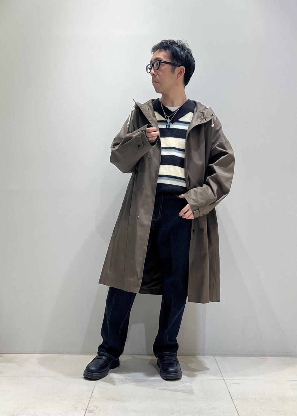 グリーン系のニット/セーター、ブラック系のローファー、ブルー系のデニムパンツを着用したメンズの冬コーディネートの5枚目の写真