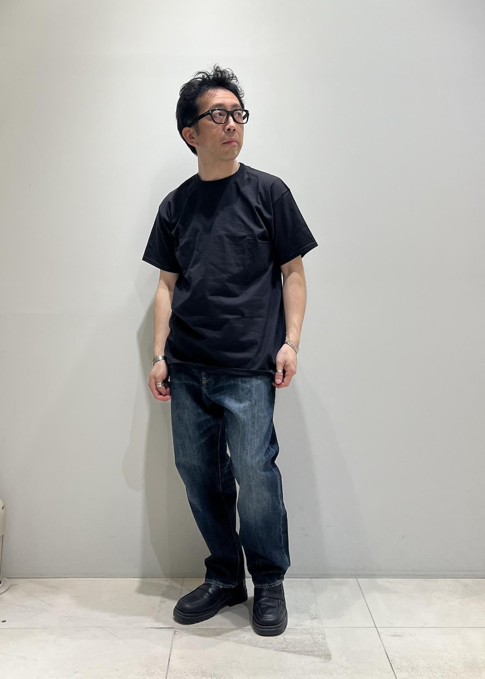 ブルー系のデニムパンツ、ホワイト系のシャツ/ブラウス、ブラック系のTシャツ/カットソーを着用したメンズの春コーディネートの2枚目の写真