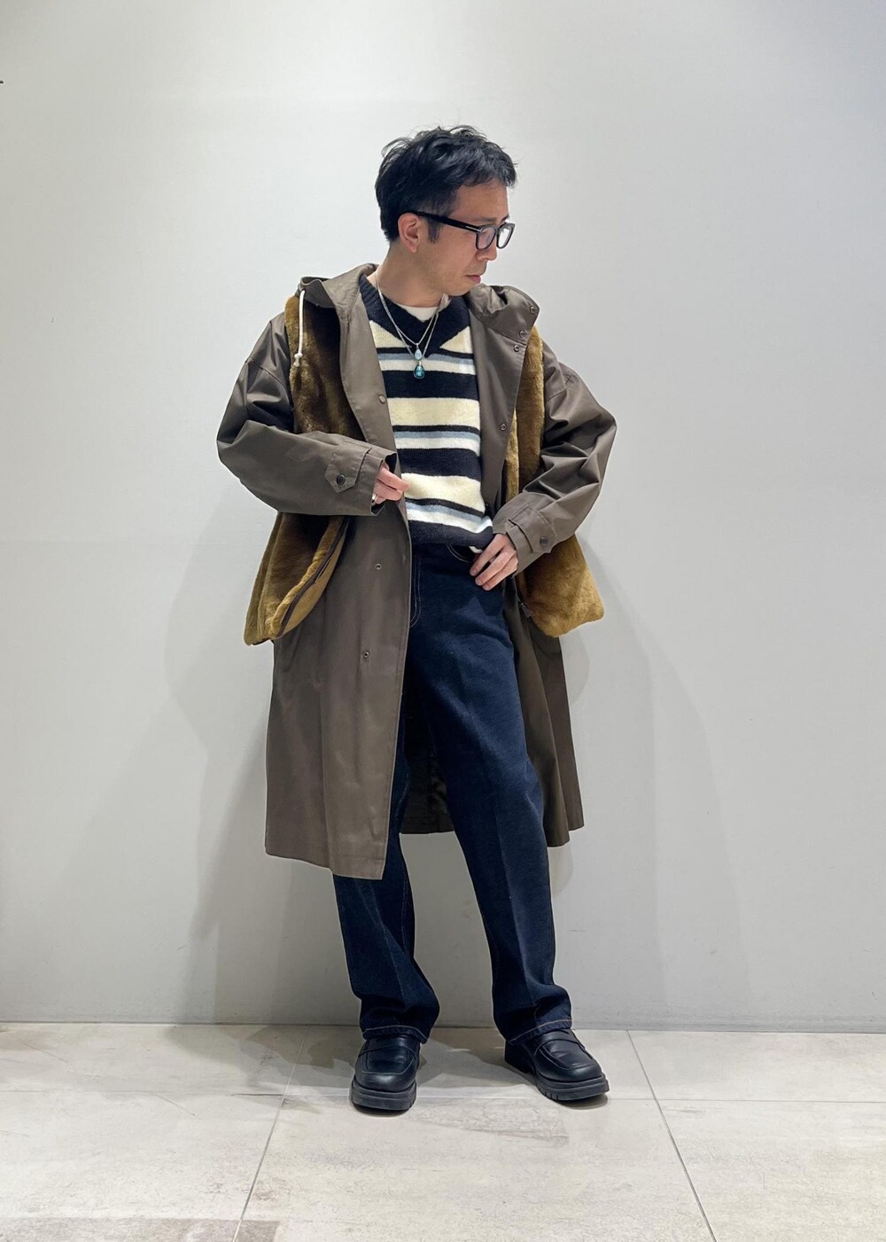 グリーン系のニット/セーター、ブラック系のローファー、ブルー系のデニムパンツを着用したメンズの冬コーディネートの4枚目の写真