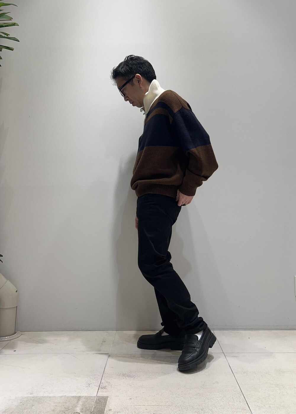 ブラック系のローファー、イエロー系のその他アウター、ブラウン系のニット/セーターを着用したメンズの冬コーディネートの2枚目の写真