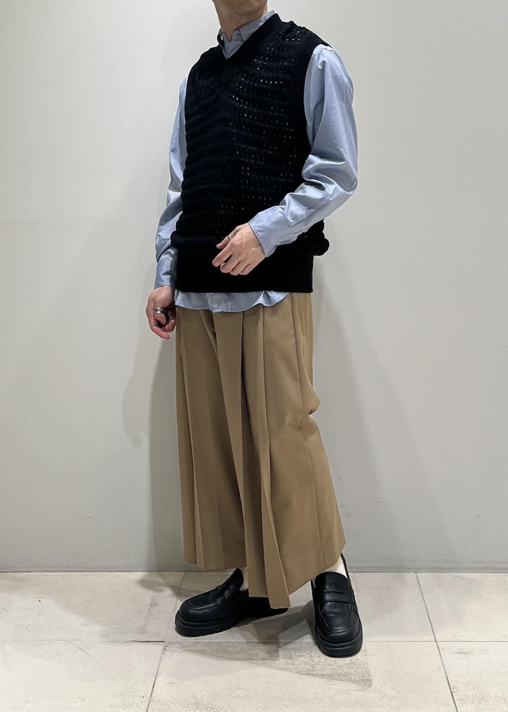 ブラック系のベスト、グレー系のステンカラーコート、イエロー系のスラックスを着用したメンズの春コーディネートの7枚目の写真