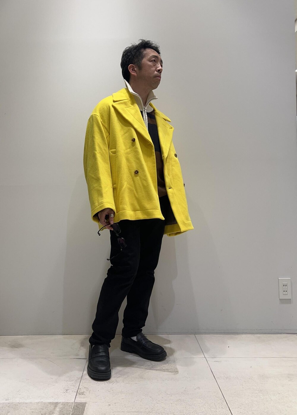 ブラック系のローファー、イエロー系のその他アウター、ブラウン系のニット/セーターを着用したメンズの冬コーディネートの5枚目の写真