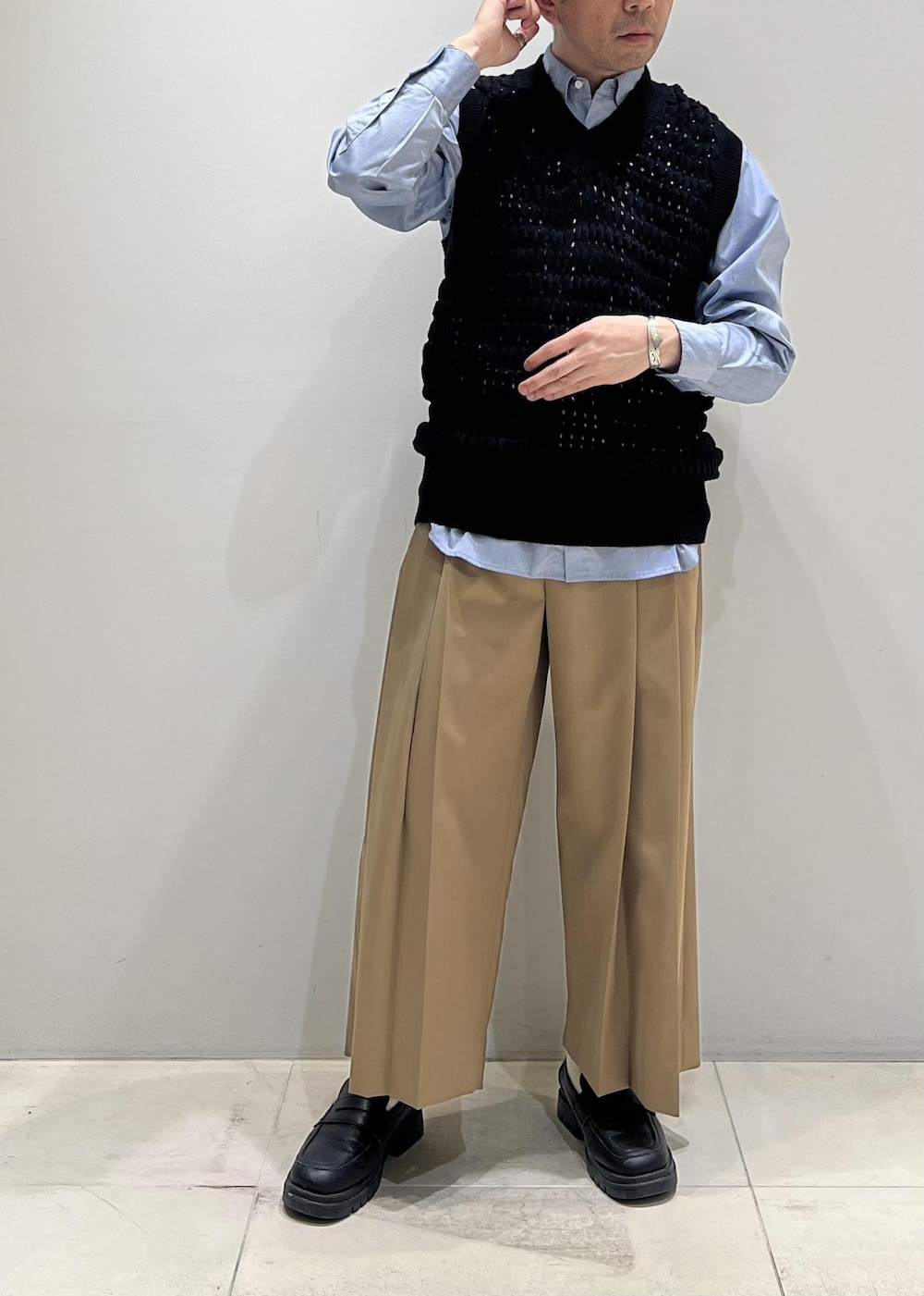 ブラック系のベスト、グレー系のステンカラーコート、イエロー系のスラックスを着用したメンズの春コーディネートの10枚目の写真