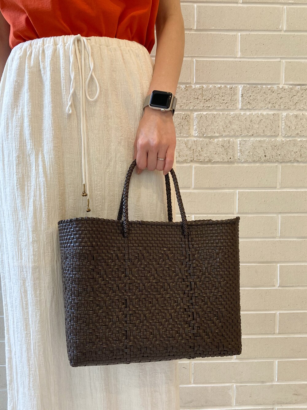 オレンジ系のTシャツ/カットソー、ブラウン系のサンダル、ホワイト系のスカートを着用したレディースの春コーディネートの5枚目の写真