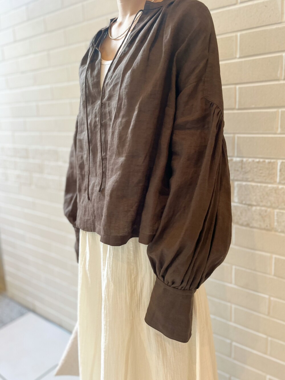 ブラウン系のシャツ/ブラウス、ベージュ系のハンドバッグ、ホワイト系のスカートを着用したレディースの春コーディネートの4枚目の写真