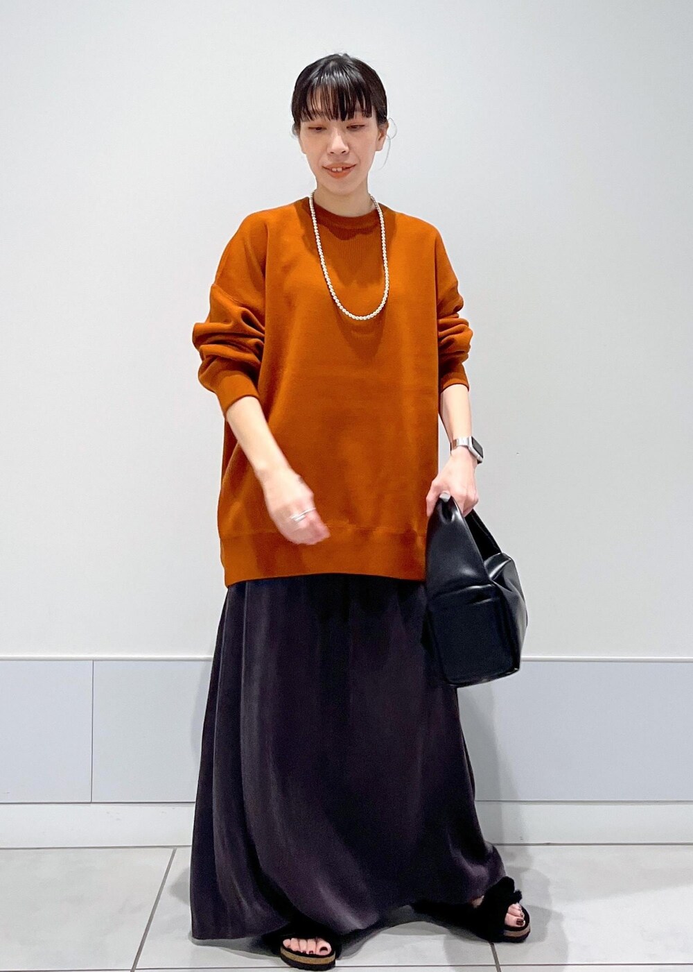 ブラック系のハンドバッグ、ブラック系のサンダル、レッド系のスウェットを着用したレディースの夏コーディネートの2枚目の写真