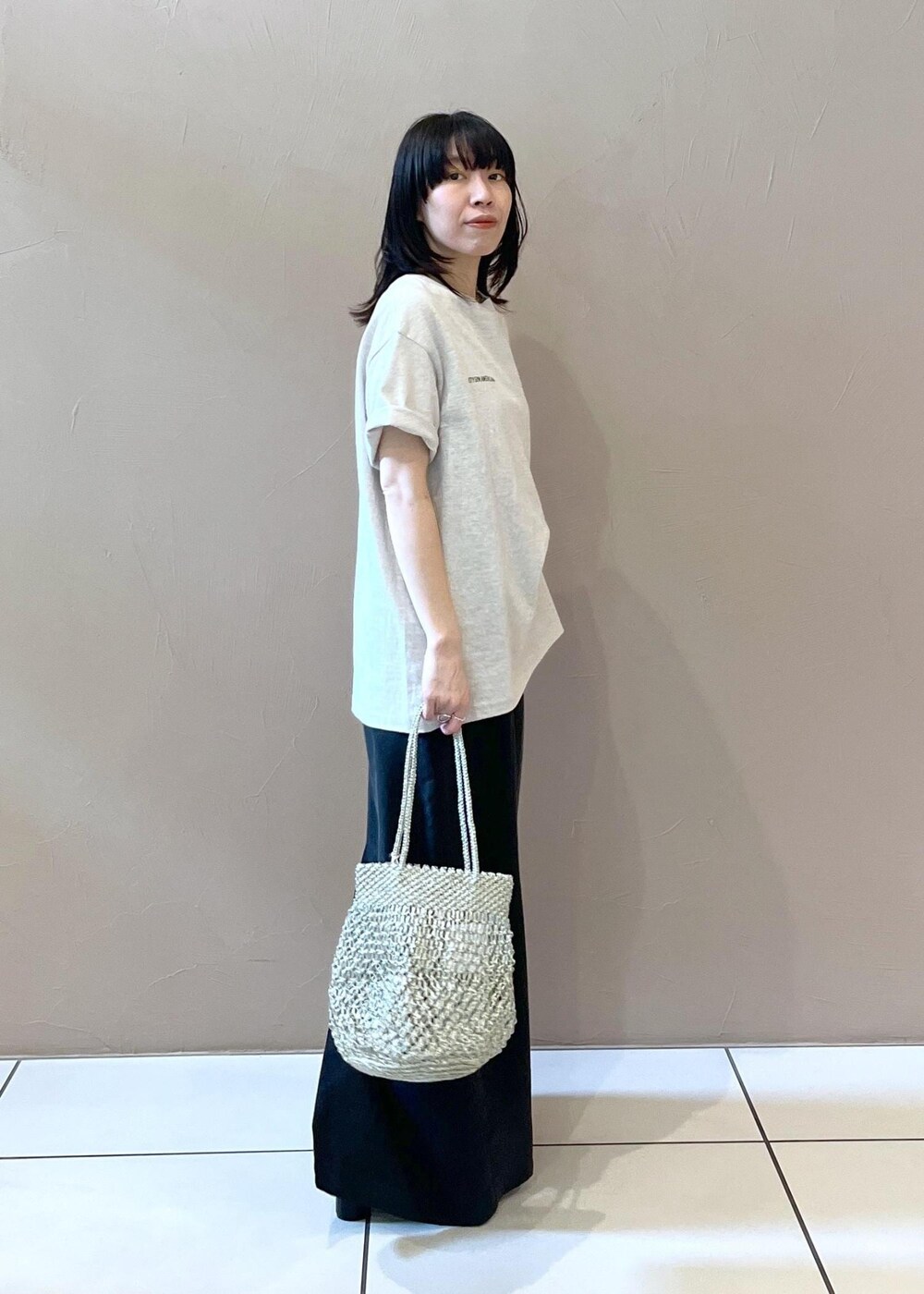 ブラック系のワンピース、ホワイト系のTシャツ/カットソー、シルバー系のトートバッグを着用したレディースの春コーディネートの2枚目の写真