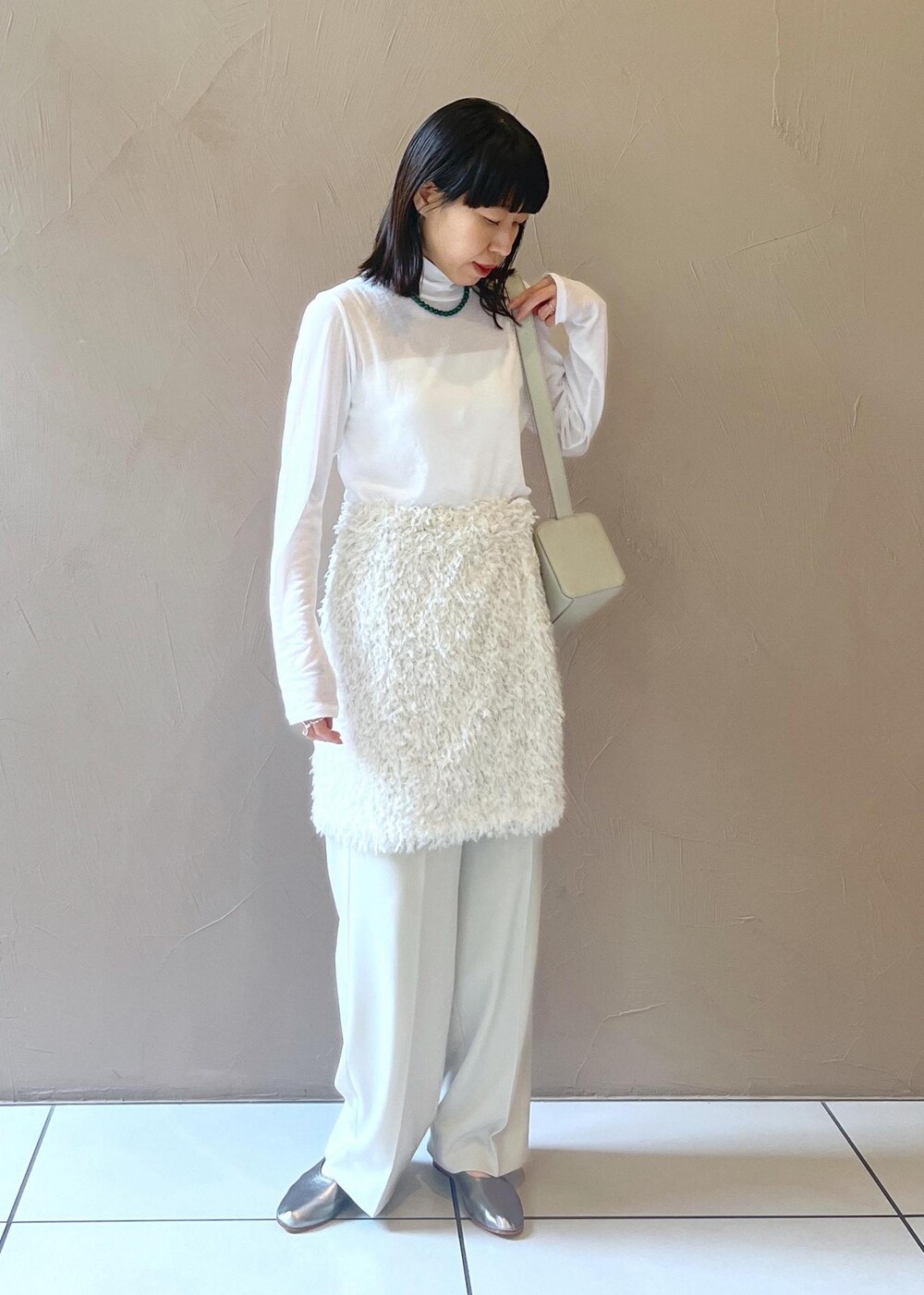 グレー系のショルダーバッグ、ホワイト系のスカート、ベージュ系のその他パンツを着用したレディースの秋コーディネートの3枚目の写真