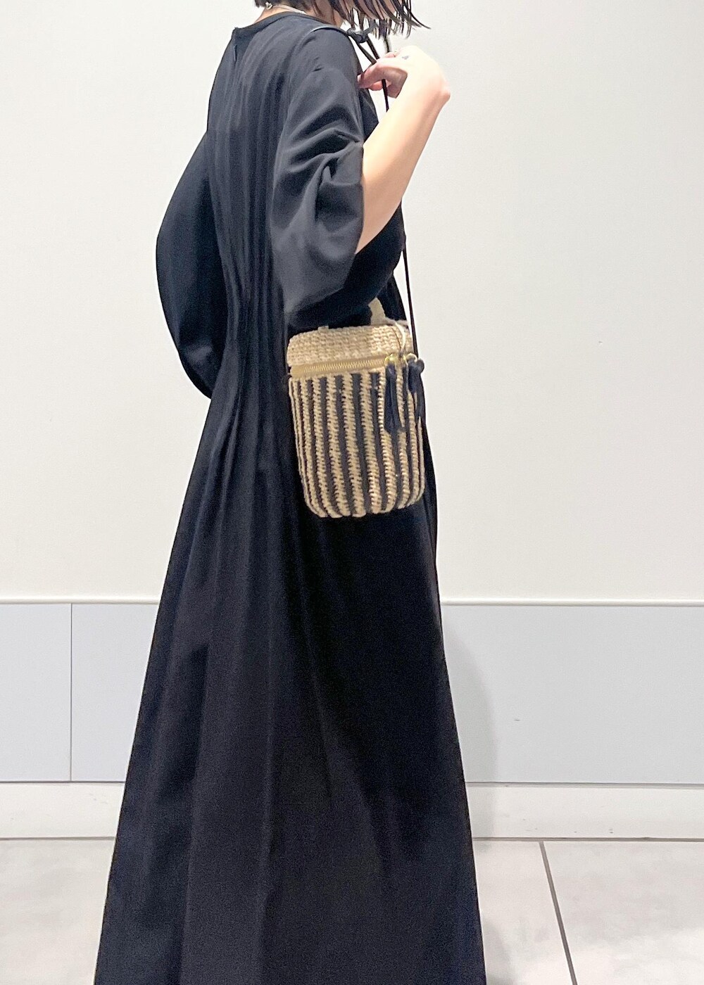 ブラック系のワンピース、ブラック系のサンダル、ホワイト系のショルダーバッグを着用したレディースの春コーディネートの3枚目の写真