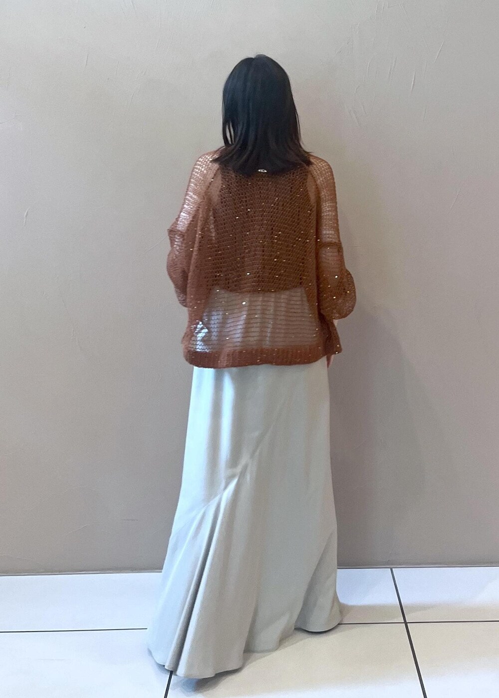 グレー系のタンクトップ、ブラウン系のカーディガン/ボレロ、ベージュ系のスカートを着用したレディースの夏コーディネートの3枚目の写真