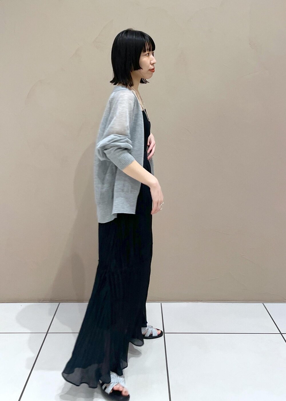 シルバー系のサンダル、ブラック系のスカート、グレー系のカーディガン/ボレロを着用したレディースの春コーディネートの2枚目の写真