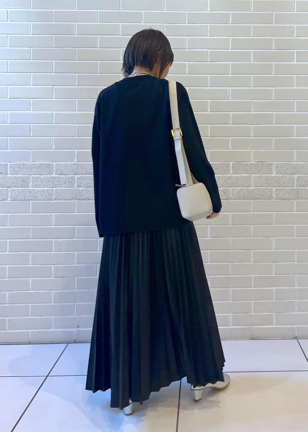 ブラック系のスカート、グレー系のショルダーバッグ、シルバー系のブーツを着用したレディースの秋コーディネートの2枚目の写真