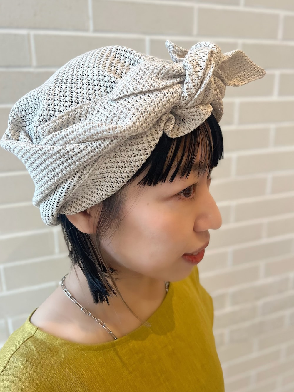 グリーン系のワンピース、ベージュ系のかごバッグ、ベージュ系のヘアアクセサリーを着用したレディースの夏コーディネートの5枚目の写真