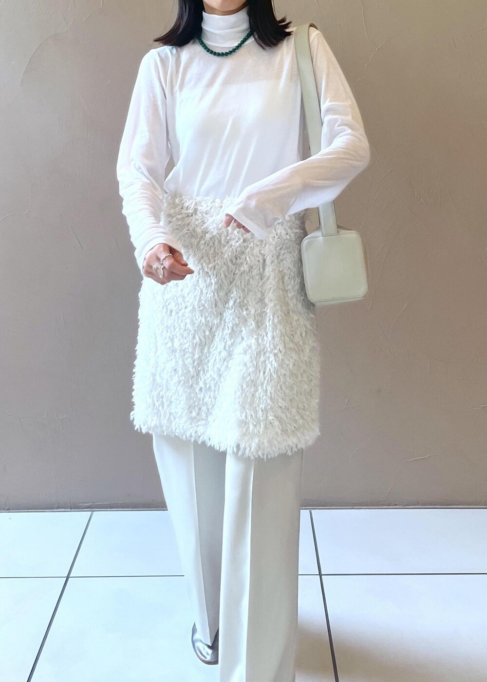 グレー系のショルダーバッグ、ホワイト系のスカート、ベージュ系のその他パンツを着用したレディースの秋コーディネートの6枚目の写真