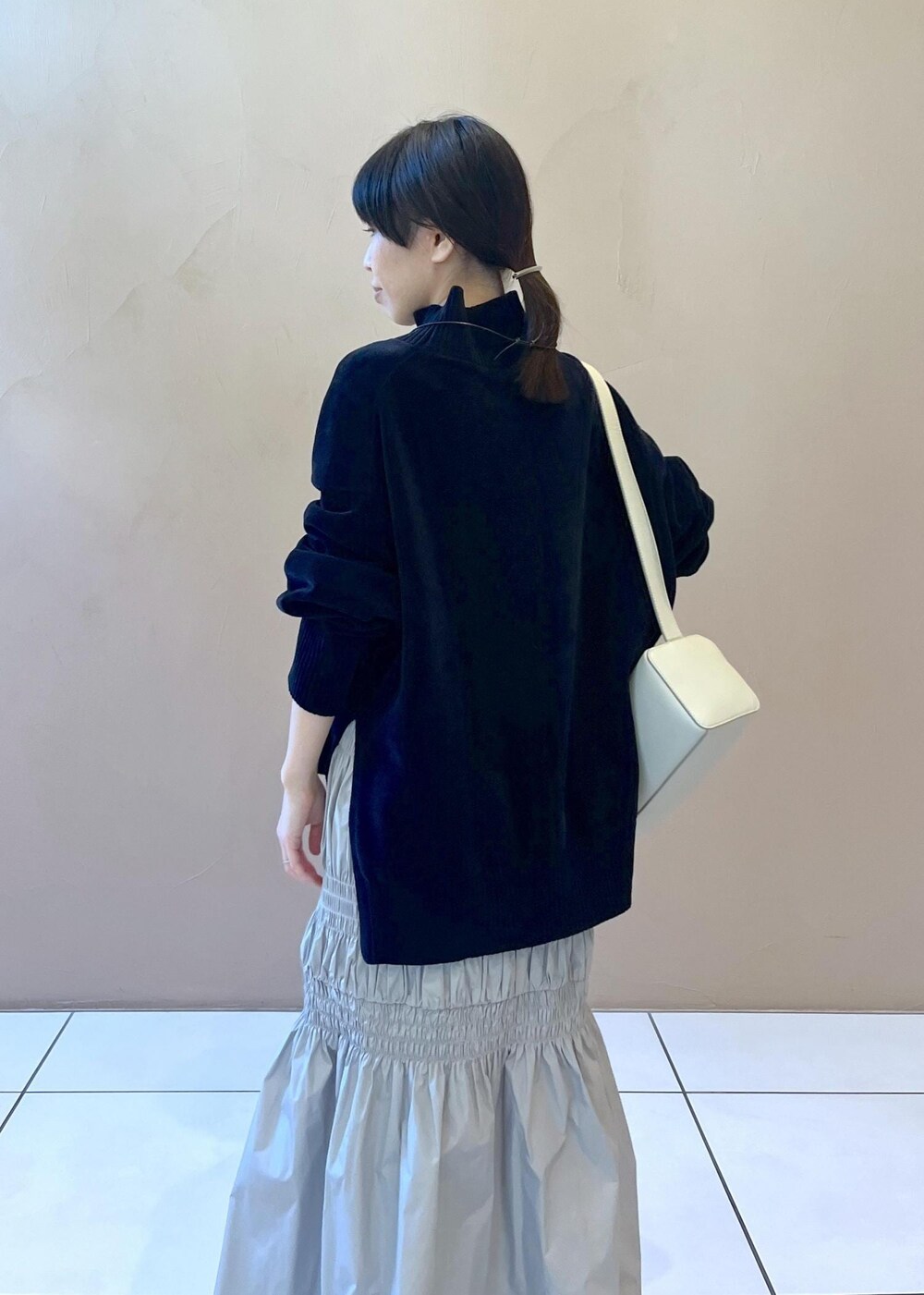 グレー系のショルダーバッグ、ブラック系のニット/セーター、グレー系のスカートを着用したレディースの冬コーディネートの5枚目の写真