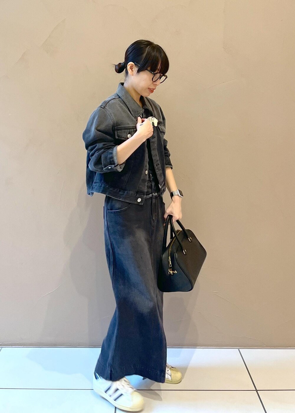 ブラック系のボストンバッグ、グレー系のデニムスカート、グレー系のデニムジャケットを着用したレディースの秋コーディネートの4枚目の写真