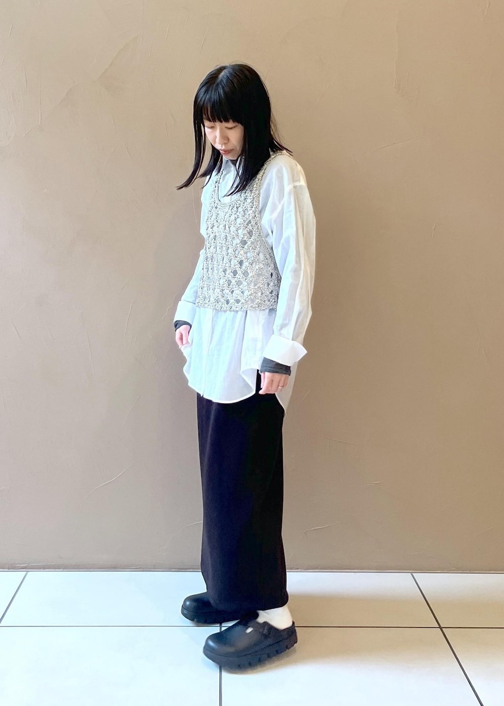 ブラック系のスカート、シルバー系のベスト、ホワイト系のシャツ/ブラウスを着用したレディースの秋コーディネートの3枚目の写真