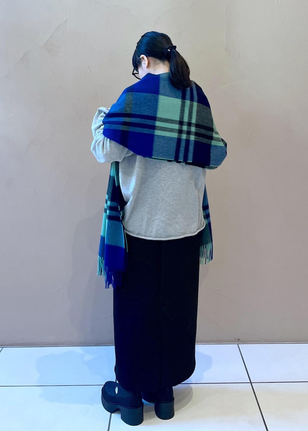 ブラック系のスカート、ブラック系のブーツ、グリーン系のストール/ショールを着用したレディースの冬コーディネートの2枚目の写真