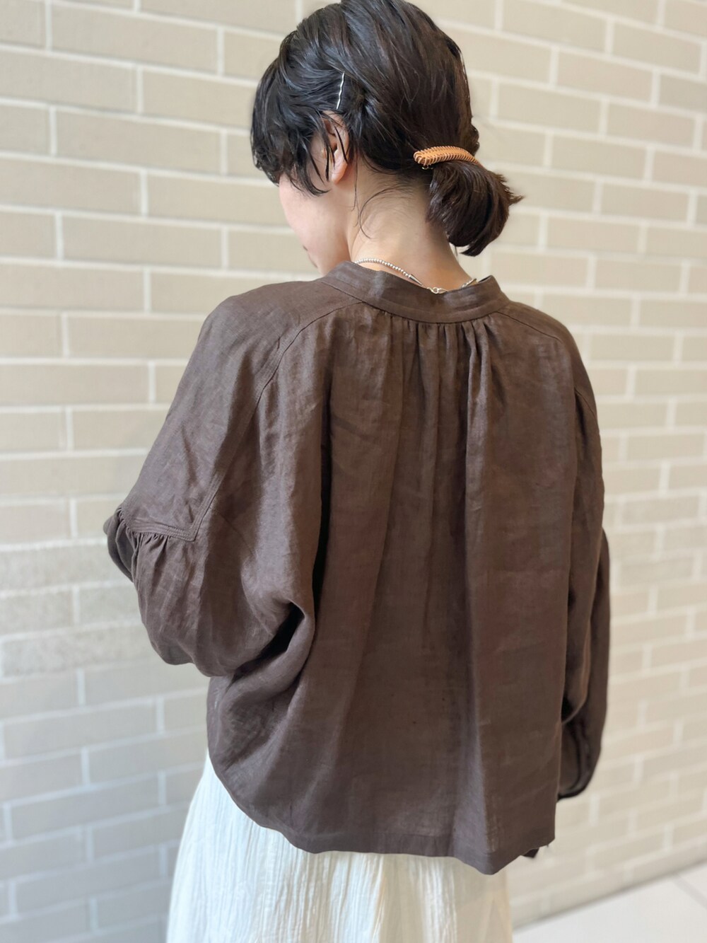 ブラウン系のシャツ/ブラウス、ベージュ系のハンドバッグ、ホワイト系のスカートを着用したレディースの春コーディネートの5枚目の写真