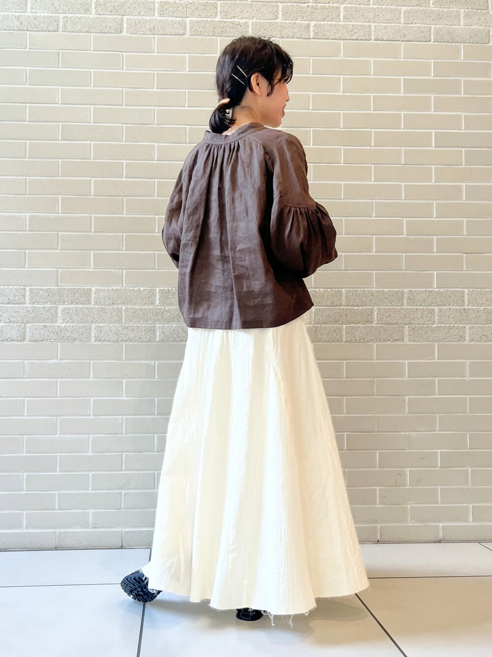 ブラウン系のシャツ/ブラウス、ベージュ系のハンドバッグ、ホワイト系のスカートを着用したレディースの春コーディネートの3枚目の写真