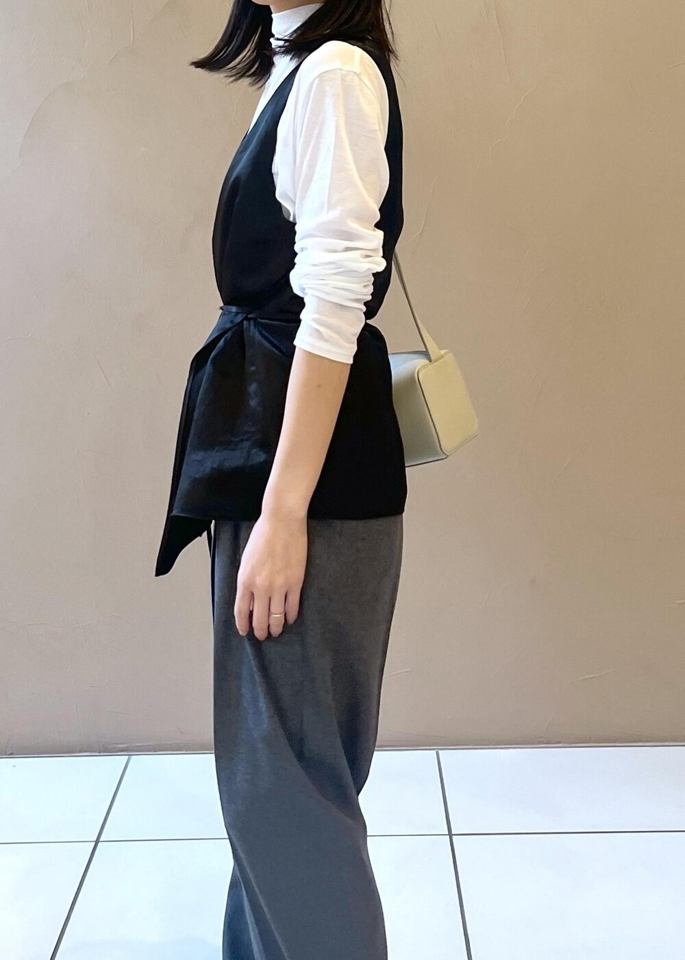 グレー系のショルダーバッグ、ブラック系のTシャツ/カットソー、グレー系のスラックスを着用したレディースの秋コーディネートの7枚目の写真