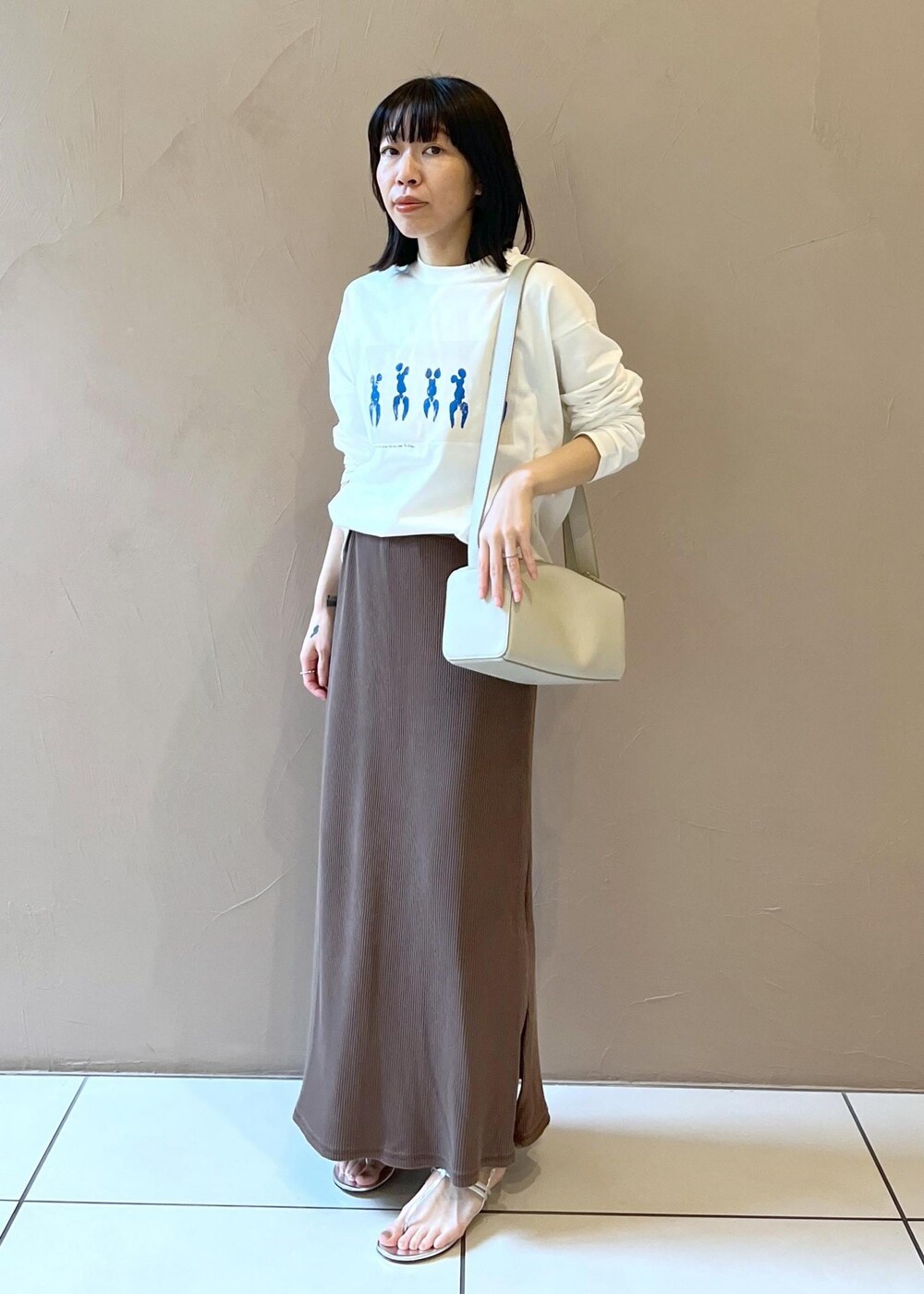 シルバー系のサンダル、ブラウン系のスカート、グレー系のショルダーバッグを着用したレディースの夏コーディネートの2枚目の写真