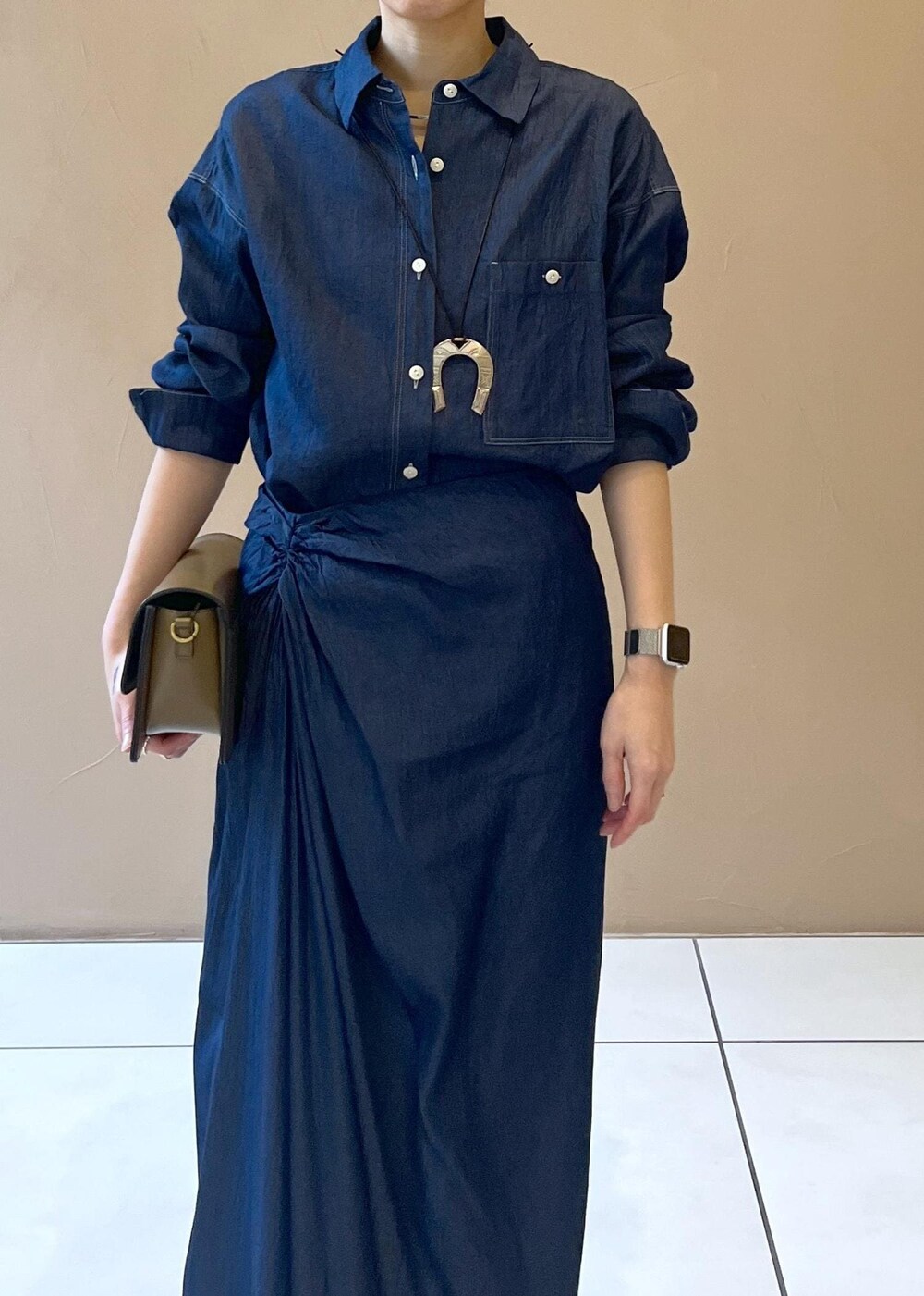 ブラウン系のショルダーバッグ、ベージュ系のパンプス、ブルー系のシャツ/ブラウスを着用したレディースの冬コーディネートの6枚目の写真