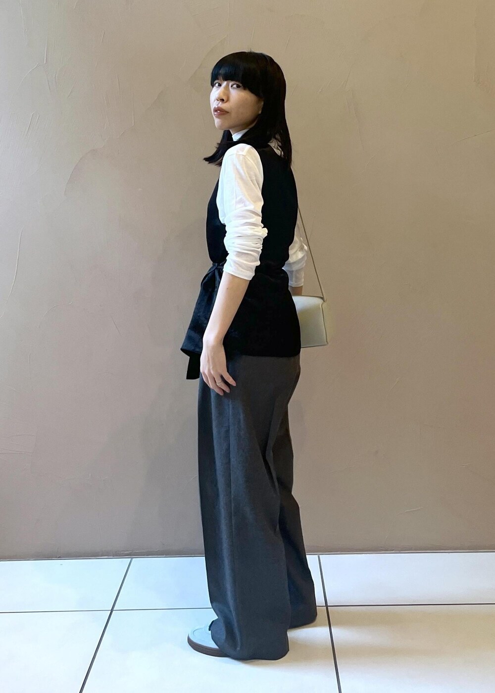 グレー系のショルダーバッグ、ブラック系のTシャツ/カットソー、グレー系のスラックスを着用したレディースの秋コーディネートの2枚目の写真